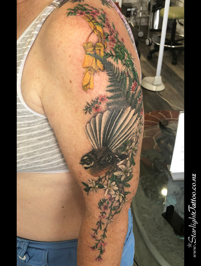 Fantail bird and NZ flora in sleeve tattoo