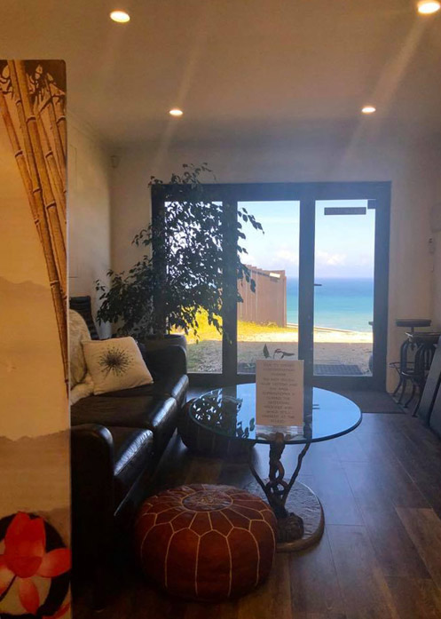 Comfortable tattoo lounge with sofa, table and ocean view